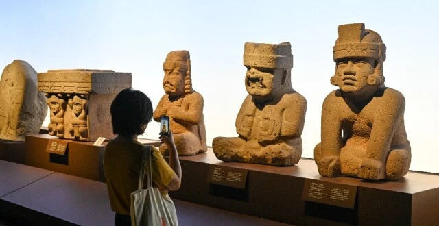 展厅内一排中美洲石雕人像，观众拍照